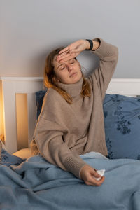 Sick woman checking temperature at home