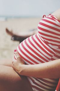 Midsection of woman sitting on beach