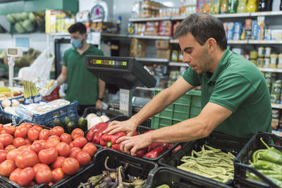 A shopkeeper placing fruit in the greengrocer's