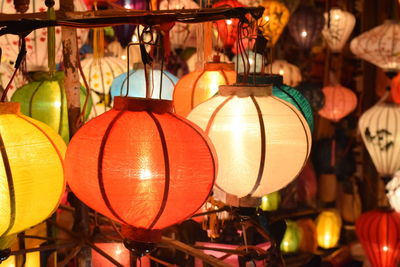 Close-up of illuminated lanterns hanging for sale at night