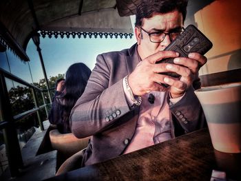 Young man using mobile phone while sitting outdoors