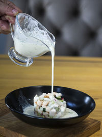 Cropped hand making okroshka at wooden table