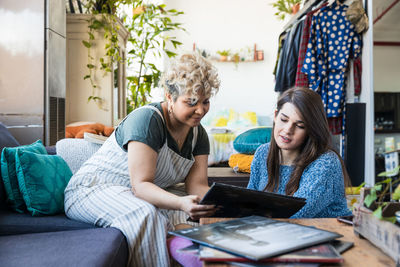 Female friends reading magazine while sitting in living room at home