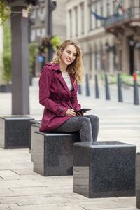 Portrait of young woman sitting on road