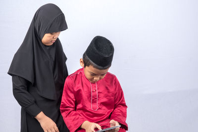 Siblings using digital tablet against white background