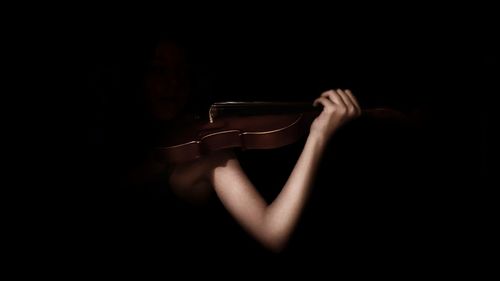 Woman playing violin against black background