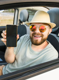 Portrait of young man using mobile phone while sitting in car