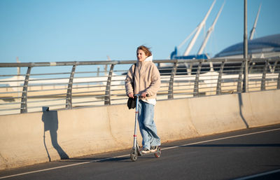 Man walking on bridge against sky in city