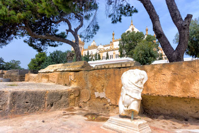 Statue against retaining wall with church in background