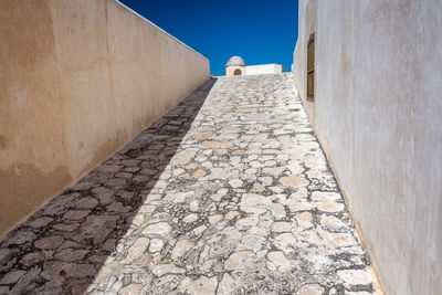Empty footpath leading towards fort san miguel during sunny day