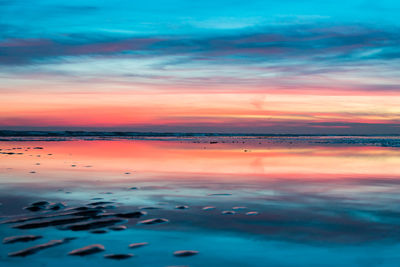 Scenic view of sea against dramatic sky during sunset