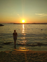 Man standing on beach against sky during sunset