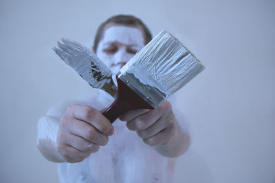 Man with body paint holding paint brush against white background