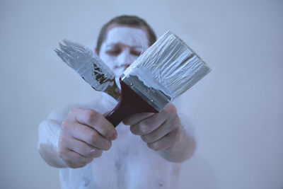 Close-up of man holding hands over white background