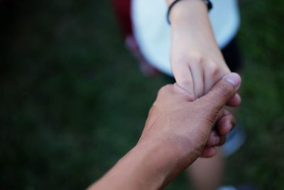 Close-up of couple holding hands against blurred background