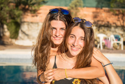 Portrait of happy friends against swimming pool