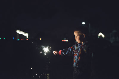 Boy holding sparkler at night