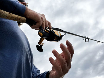 Low angle view of cropped hand against sky