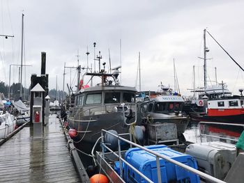 Boats moored at harbor against sky