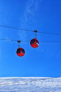 Low angle view of umbrellas hanging against clear blue sky