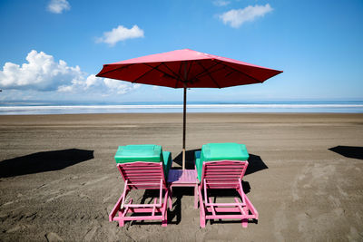 Deck chairs on beach against sky