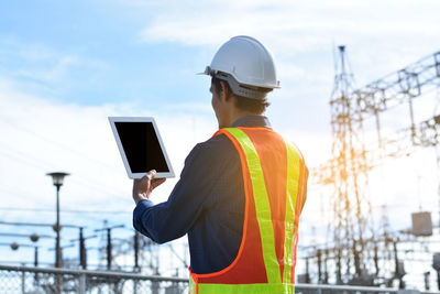 Rear view of man using mobile phone against sky