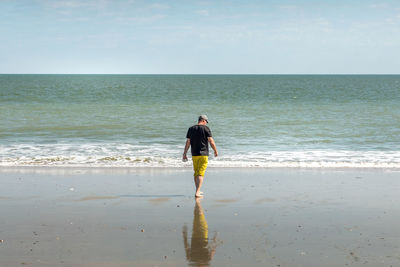 Rear view full length of man walking on shore at beach