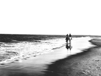 Man riding horse on beach against clear sky