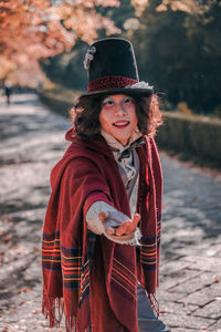 Portrait of smiling young woman cosplaying mad hatter in top hat during winter