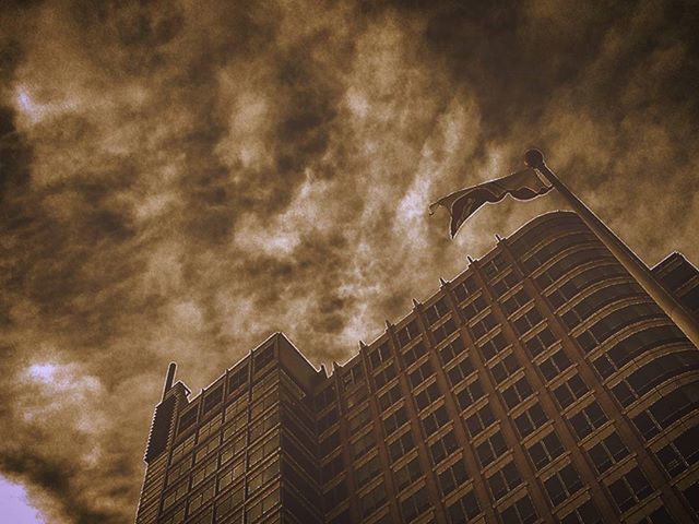 low angle view, architecture, building exterior, built structure, sky, cloud - sky, cloudy, building, city, tower, modern, tall - high, cloud, office building, weather, outdoors, high section, skyscraper, overcast, dusk
