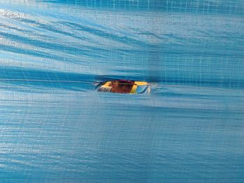 Man looking through torn blue tarpaulin