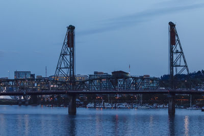 Bridge over river against sky in city