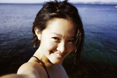 Portrait of a smiling young woman against calm sea