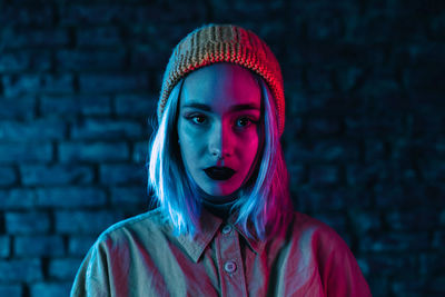 Portrait of woman standing against brick wall