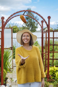 Portrait of smiling young woman holding yellow while standing outdoors