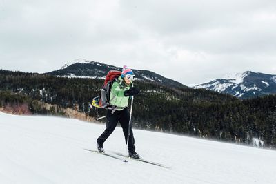Woman skiing on snow covered mountain against sky