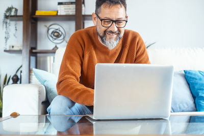 Man using laptop while sitting on sofa at home