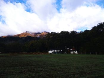 Scenic view of green field and mountains against sky