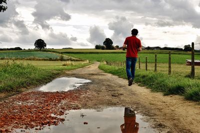 Rear view of man standing on field against sky