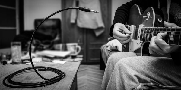 Midsection of man playing guitar at home