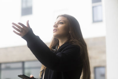 Young woman with long hair outside with smart phone