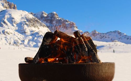 Close-up of bonfire against mountain in winter