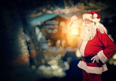 Man in santa claus costume holding illuminated lantern