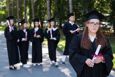 Portrait of smiling friends wearing graduation gown