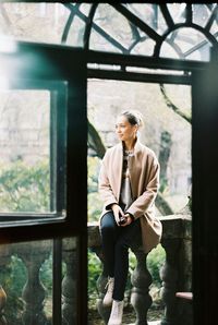 Full length of woman sitting on window