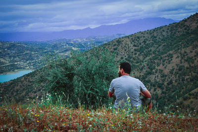 Rear view of man sitting on mountain