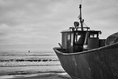 Ship moored on beach against sky