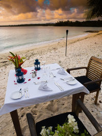 High angle view of place setting on table at sandy beach during sunset