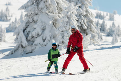 Full length of father and son skiing on snow during winter