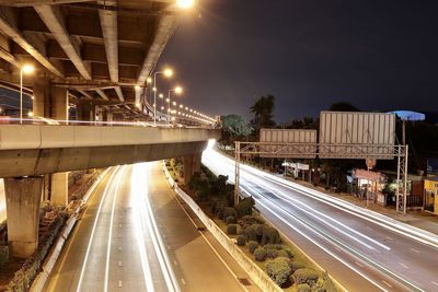 Light trails on road in city against sky at night